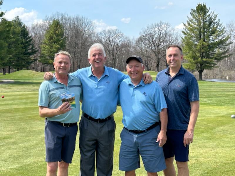 4 golfers smiling at the camera.