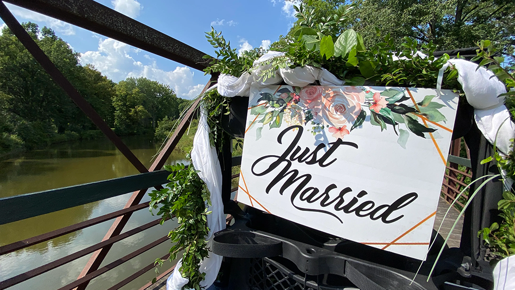 Just Married Sign draped in florals and greenery on cart path